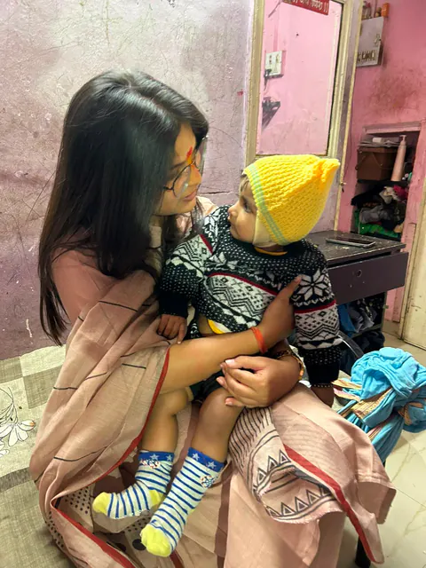 Siddhali Anup Shah holding a child during a neighbourhood visit