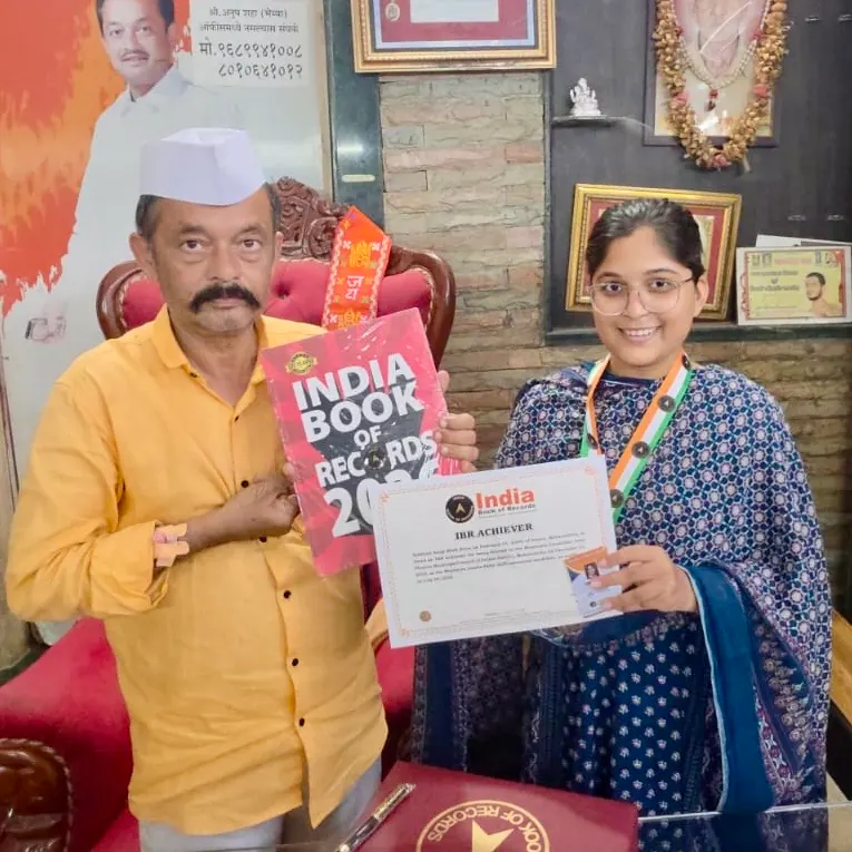 Siddhali Anup Shah holding her Indian Book of Records certificate beside a presenter